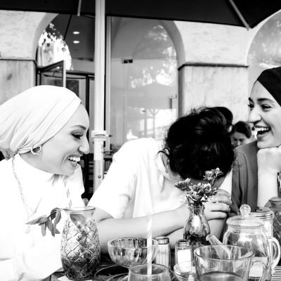 Drei Frauen sitzen mit Kaffee und Kuchen zusammen an einem Tisch in einem Café.