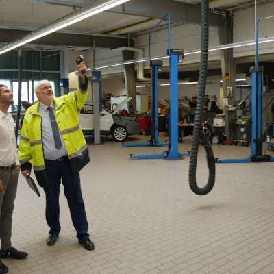 Zwei Männer stehen in einer Autowerkstatt und schauen, wie sich Energie einsparen lässt.