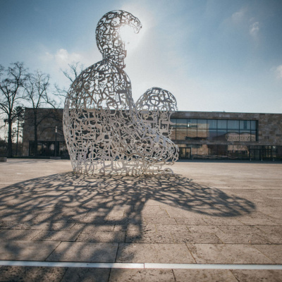 Eine große Figur steht vor einem Universitätsgebäude in Frankfurt am Main.