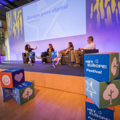 Das "Hey, Europe! Festival" in Hanau; mehrere Personen sitzen auf einer Bühne und diskutieren miteinander.