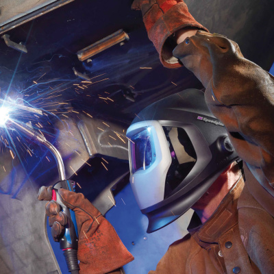 Ein Arbeiter in Schutzausrüstung verschweißt Metall-Stücke