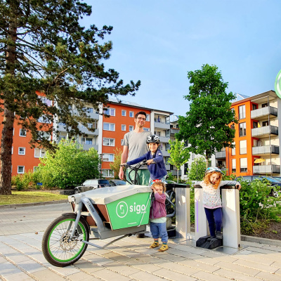 Mann mit Kindern und einem E-Bike vor einem Haus