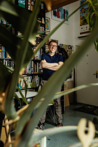 Thomas Marutschke lehnt an ein Bücherregal.