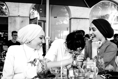 Drei Frauen sitzen mit Kaffee und Kuchen zusammen an einem Tisch in einem Café.