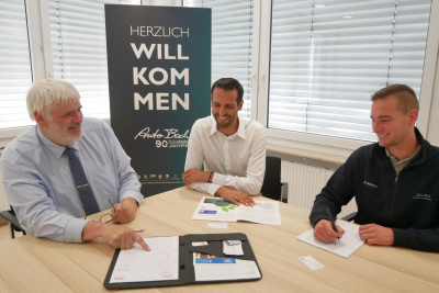 Drei Männer sitzen an einem Tisch und unterhalten sich.