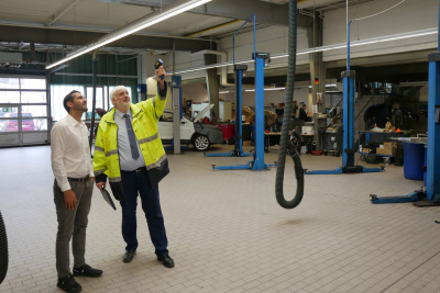 Zwei Männer stehen in einer Autowerkstatt und schauen, wie sich Energie einsparen lässt.
