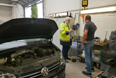 Zwei Männer unterhalten sich in einer Autowerkstatt.