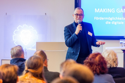 Rolf Krämer, Referatsleiter im Hessischen Wirtschaftsministerium, hält ein Mikrofon in der Hand und spricht zum Publikum.