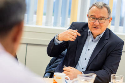 Ein Mann sitzt an einem Tisch und unterhält sich mit einem anderen Mann.