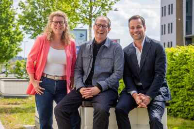 Claudia Braun, Herbert Lang und Daniel Fischer sind zu dritt auf einer Bank. Im Hintergrund sieht man Bäume, Hecke und ein Gebäude.