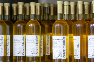 Mehrere Weinflaschen stehen nebeneinander. Auf dem Label sind verschiedene Apfelsorten genannt.