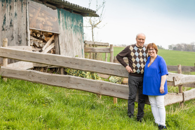 Peter Merkel und seine Frau vor einem alten Holzschuppen