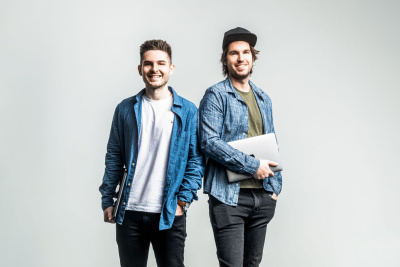 Chris und Dennis Möbus stehen vor einer grauen Wand