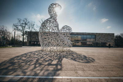 Eine große Figur steht vor einem Universitätsgebäude in Frankfurt am Main.