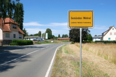 Ortsschild der gemeinde Gemünden neben einer Straße