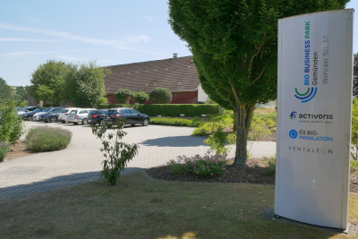 Firmenschild des Bio Business Park mit verschiedenen Firmenlogos vor einem Parkplatz