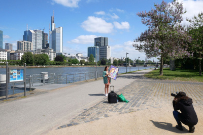 Ana Paola Paniagua steht mit ihrem Bild am Mainufer und wird fotografiert.
