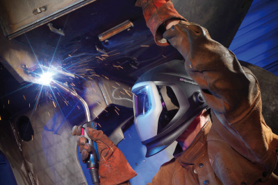 Ein Arbeiter in Schutzausrüstung verschweißt Metall-Stücke