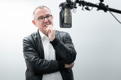 Ein Mann steht vor einem Standmikrofon.