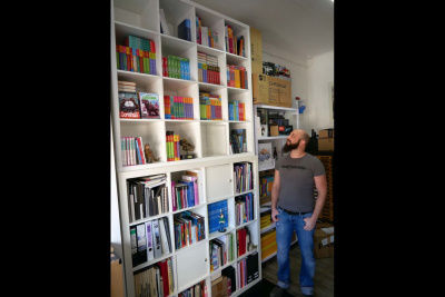 Raimund Frey steht vor seinem Bücherregal.