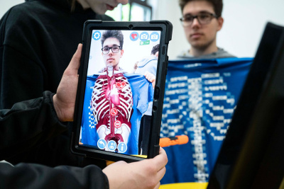 Ein Junge scannt einen anderen mit einem Programm auf dem Tablet ab.
