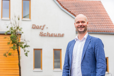 Victor Röder, Bürgermeister der Gemeinde Jossgrund, steht vor dem Haus %22Dorfscheune%22.