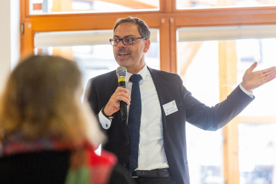 Mathias Trümner vom Hessischen Ministerium für Umwelt, Klimaschutz, Landwirtschaft und Verbraucherschutz, steht mit einem Mikrofon in der Hand auf einer Bühne und spricht zum Publikum.