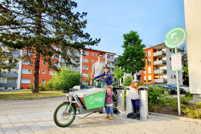 Mann mit Kindern und einem E-Bike vor einem Haus