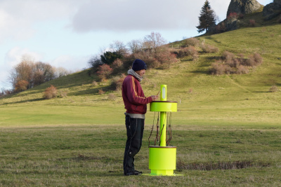 Eine mobile Handyladestation und ein Mann stehen auf einer Wiese.