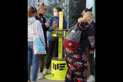 Mehrere Frauen stehen an einer mobilen Handyladestation im Freien.