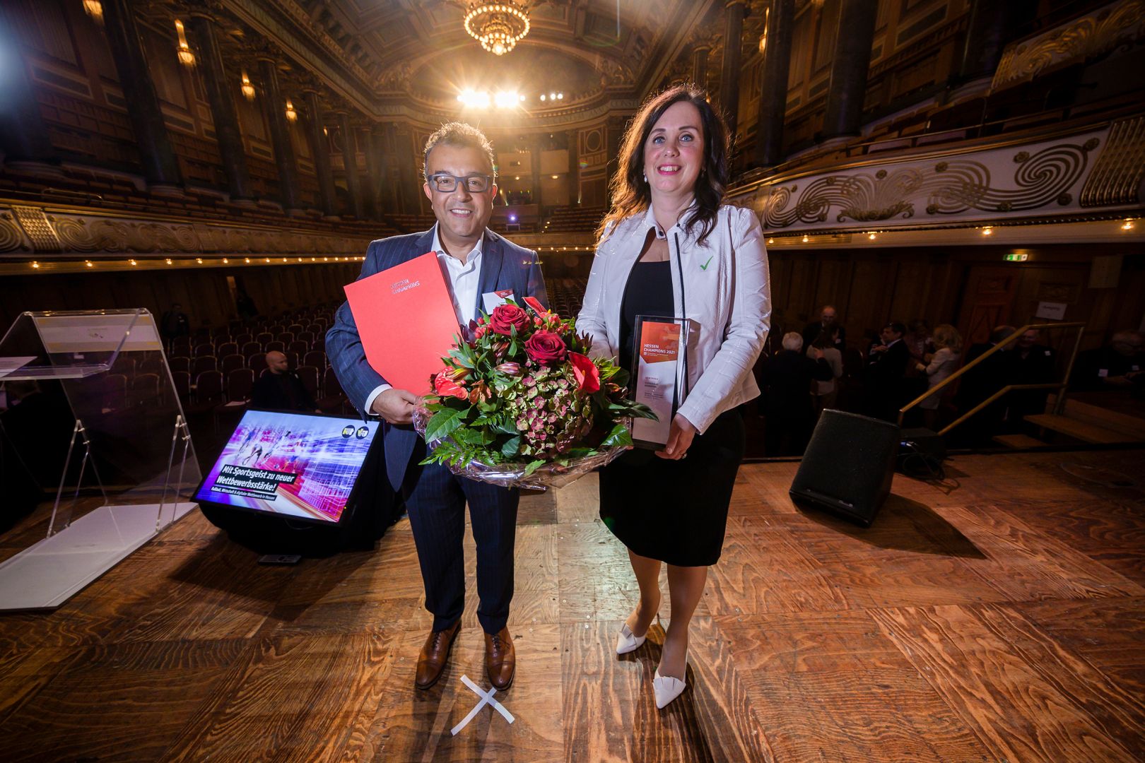 Dr. Hüseyin Aygün und Dr. Sylvia Wojczewski stehen bei der Verleihung der "Hessen Champions" 2021 auf der Bühne.