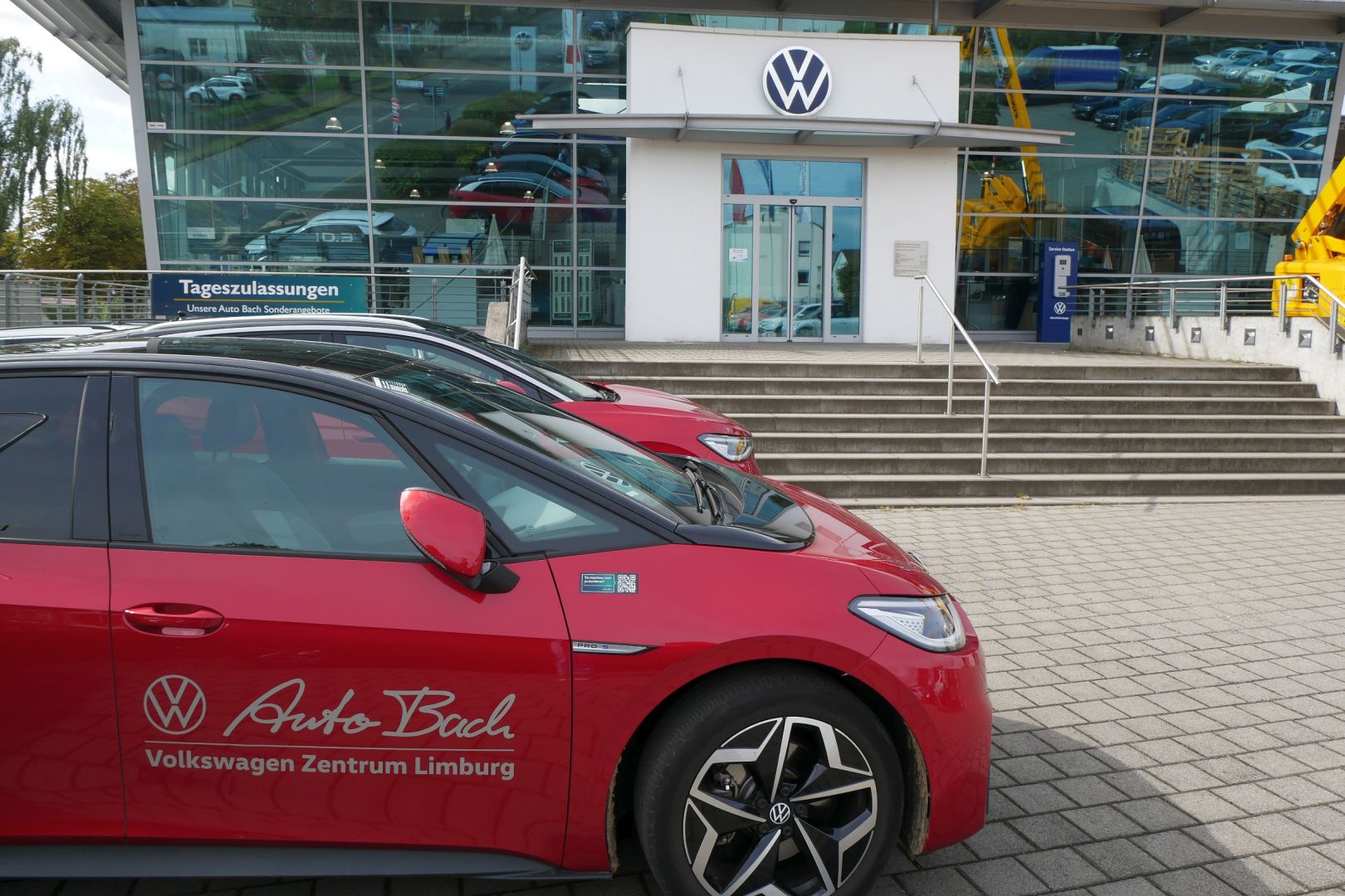 Das VW-Zentrum Limburg von außen. Es stehen zwei rote Autos vor dem Gebäude.