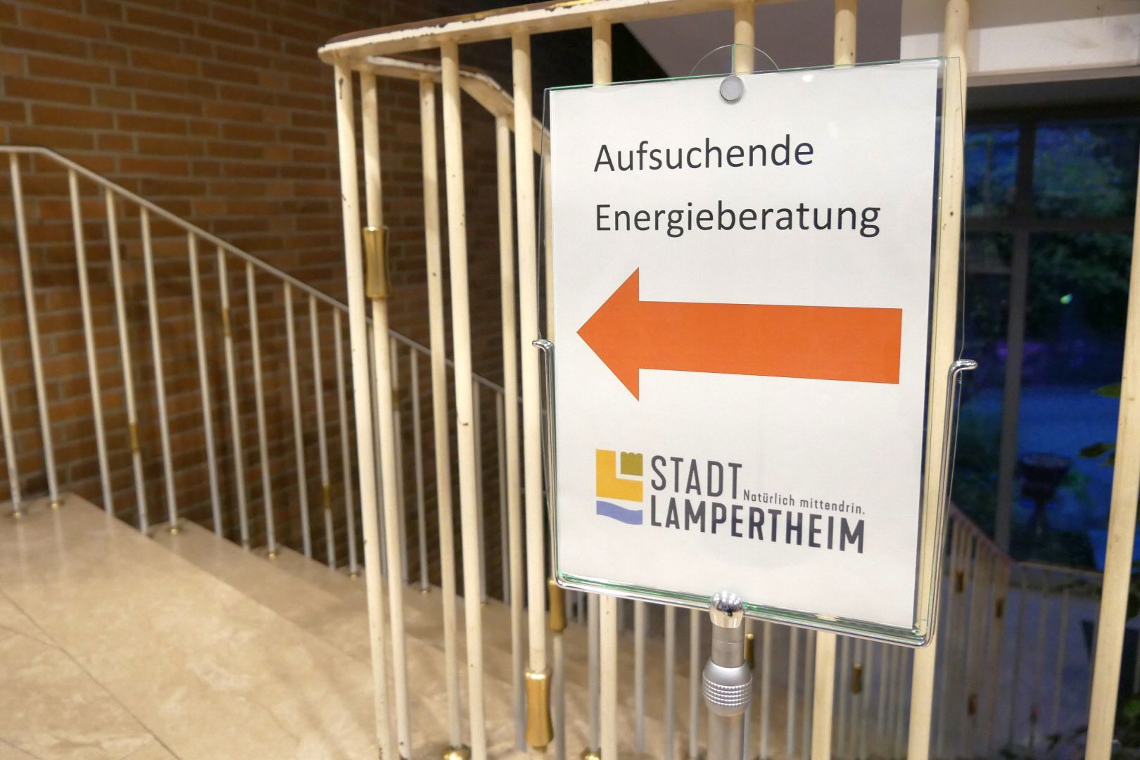 Ein Schild mit der Aufschrift „Aufsuchende Energieberatung“ hängt an einem Treppengeländer.